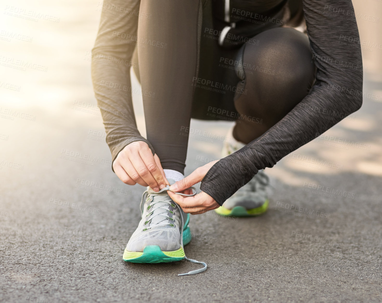 Buy stock photo Shot of an unrecognizable young woman tying her laces before a morning run