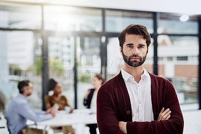 Buy stock photo Defocused shot of a young businessman posing with his colleagues sitting in the background