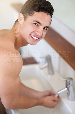 Buy stock photo Portrait of a handsome young man washing his face at the bathroom sink
