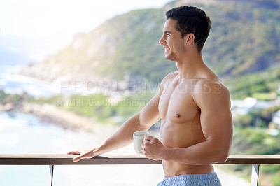 Buy stock photo Shot of a handsome young man having coffee out on the balcony in the morning