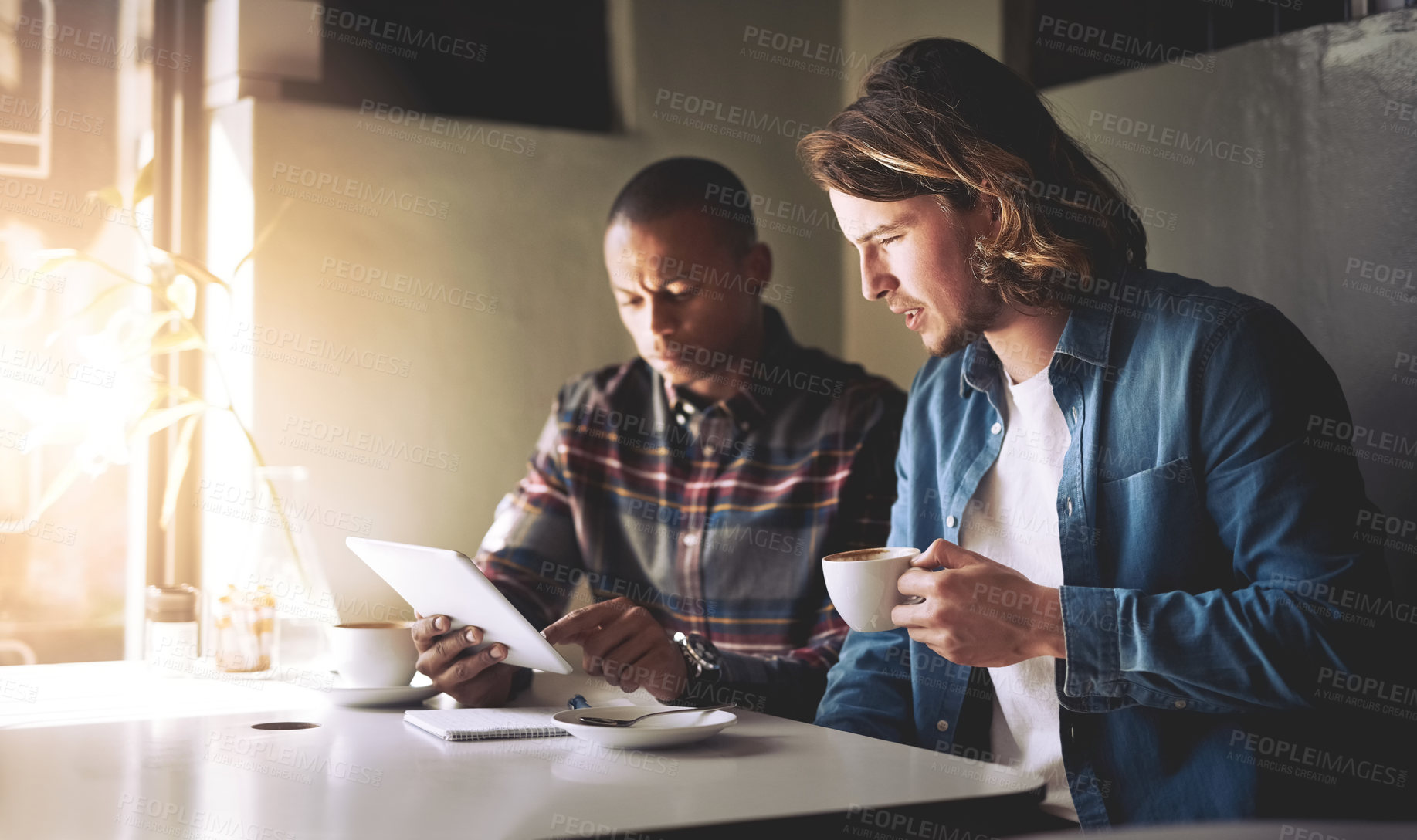 Buy stock photo Shot of  two friends using a tablet while having coffee in a coffee shop