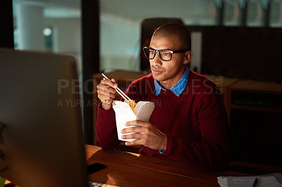 Buy stock photo Shot of a handsome young man eating Chinese food while working late in his office