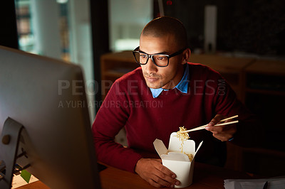 Buy stock photo Shot of a handsome young man eating Chinese food while working late in his office