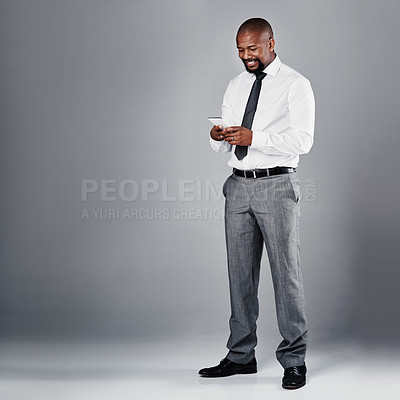 Buy stock photo Studio shot of a corporate businessman texting on his against a grey background
