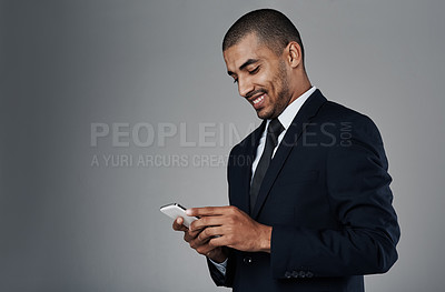 Buy stock photo Studio shot of a corporate businessman texting on his cellphone against a grey background