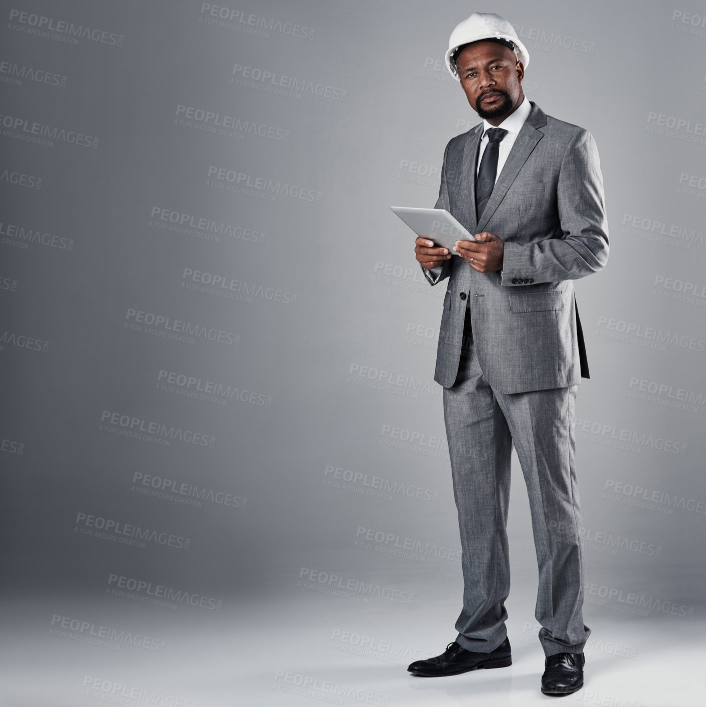 Buy stock photo Portrait of a well-dressed civil engineer using his tablet while standing in the studio