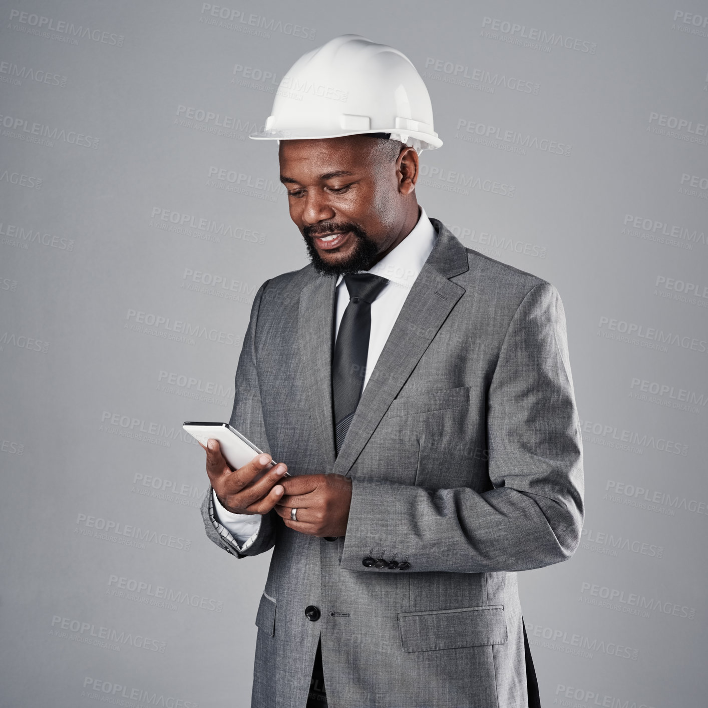 Buy stock photo Black man, phone and civil engineer with helmet for architecture, design or communication on a gray studio background. African contractor, male person or model on mobile smartphone for industrial app