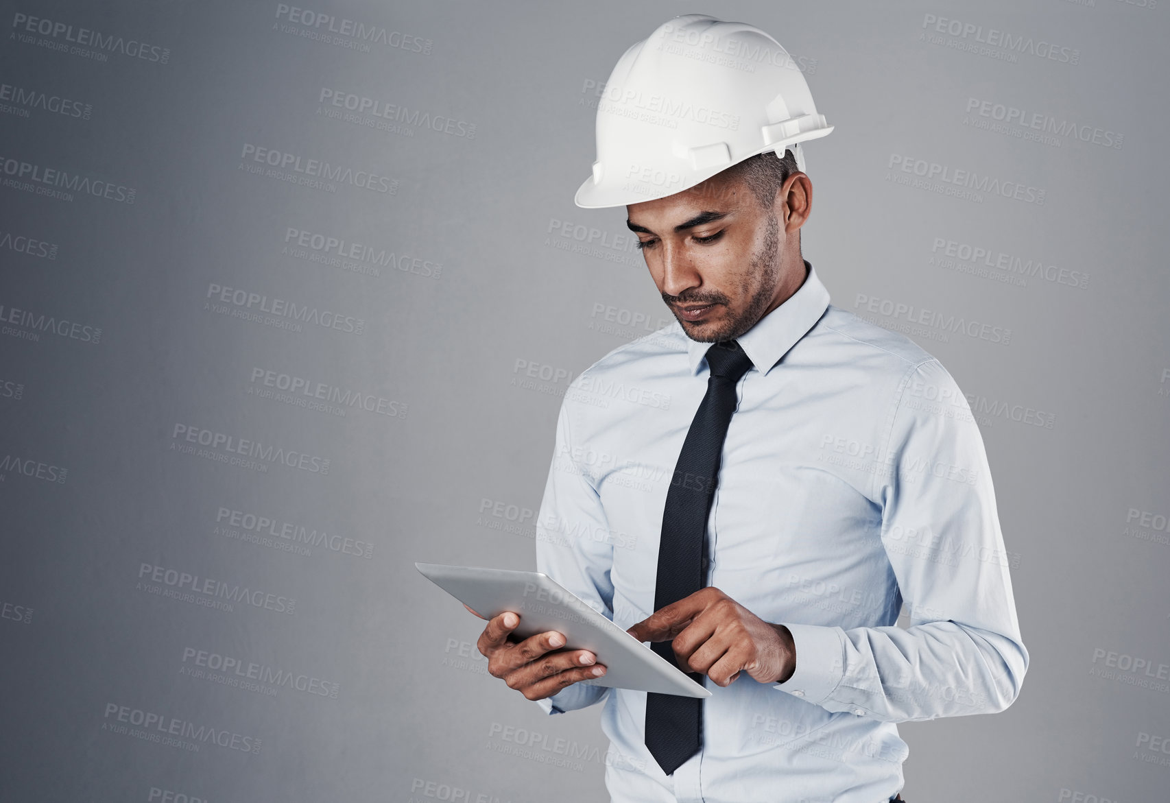 Buy stock photo Engineer, tablet and construction worker with web research and online blueprint in studio. Contractor, planning and helmet of Indian male professional with scroll, technology and grey background