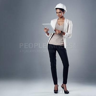 Buy stock photo Shot of a well-dressed civil engineer using her tablet while standing in the studio