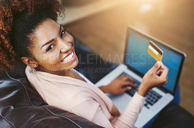 Buy stock photo High angle portrait of an attractive young woman shopping online while chilling at home on the sofa