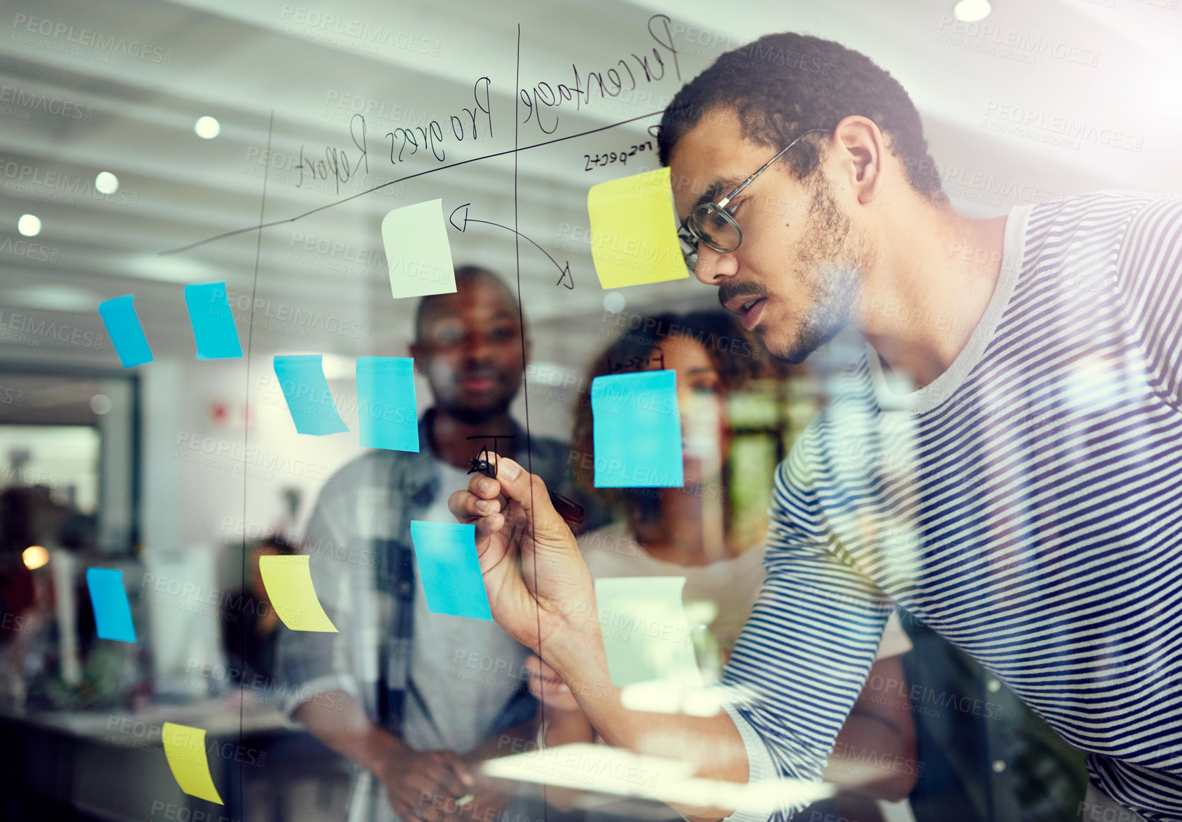 Buy stock photo Cropped shot of a group of young designers planning on a glass board