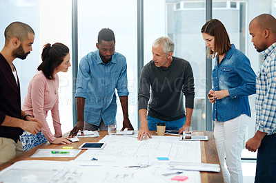 Buy stock photo Cropped shot of a group of architects working on blueprints in the boardroom