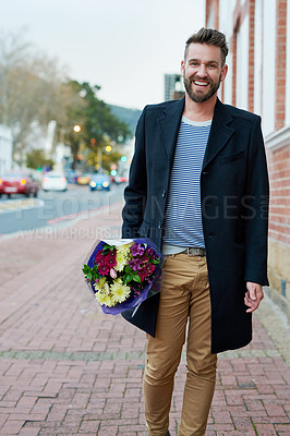 Buy stock photo Portrait of a handsome young man walking through the city with a bunch of flowers in hand