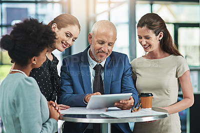 Buy stock photo Cropped shot of a group of businesspeople working together on a digital tablet in an office