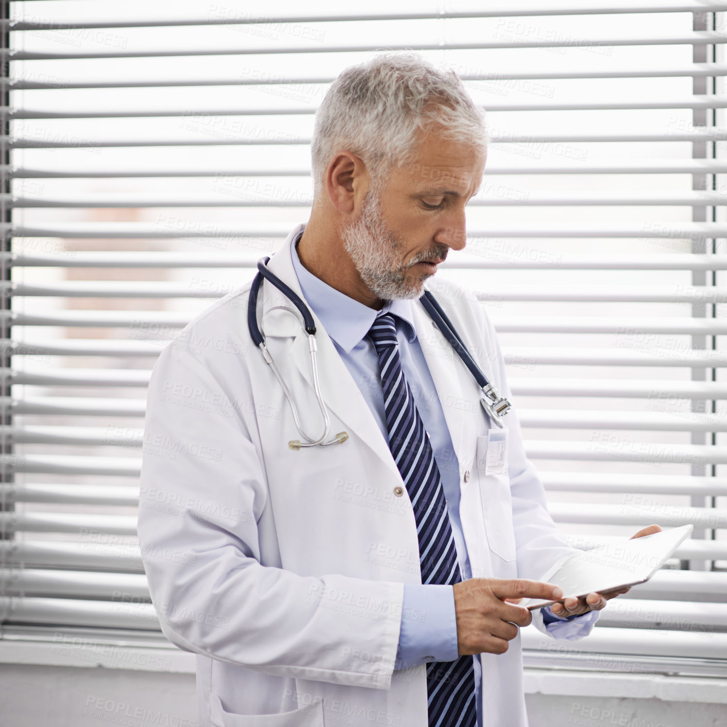 Buy stock photo Cropped shot of a mature male doctor using a digital tablet