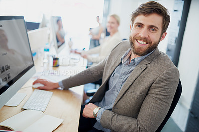 Buy stock photo Portrait of a young designer sitting at his workstation with colleagues in the background