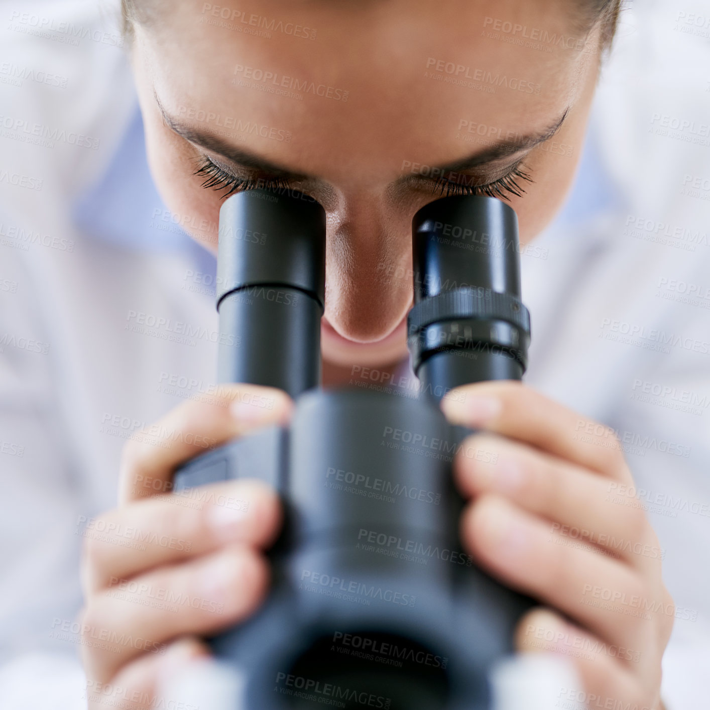 Buy stock photo Cropped shot of a young female scientist using a microscope in a lab