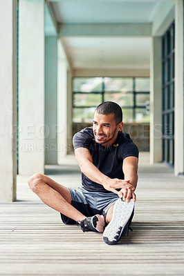Buy stock photo Shot of a sporty young man stretching outside