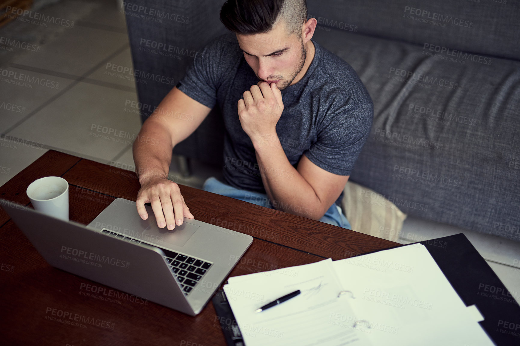 Buy stock photo Shot of a driven young man using his laptop to work from home