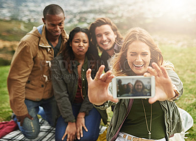 Buy stock photo Shot of a group of friends taking a selfie while standing outside