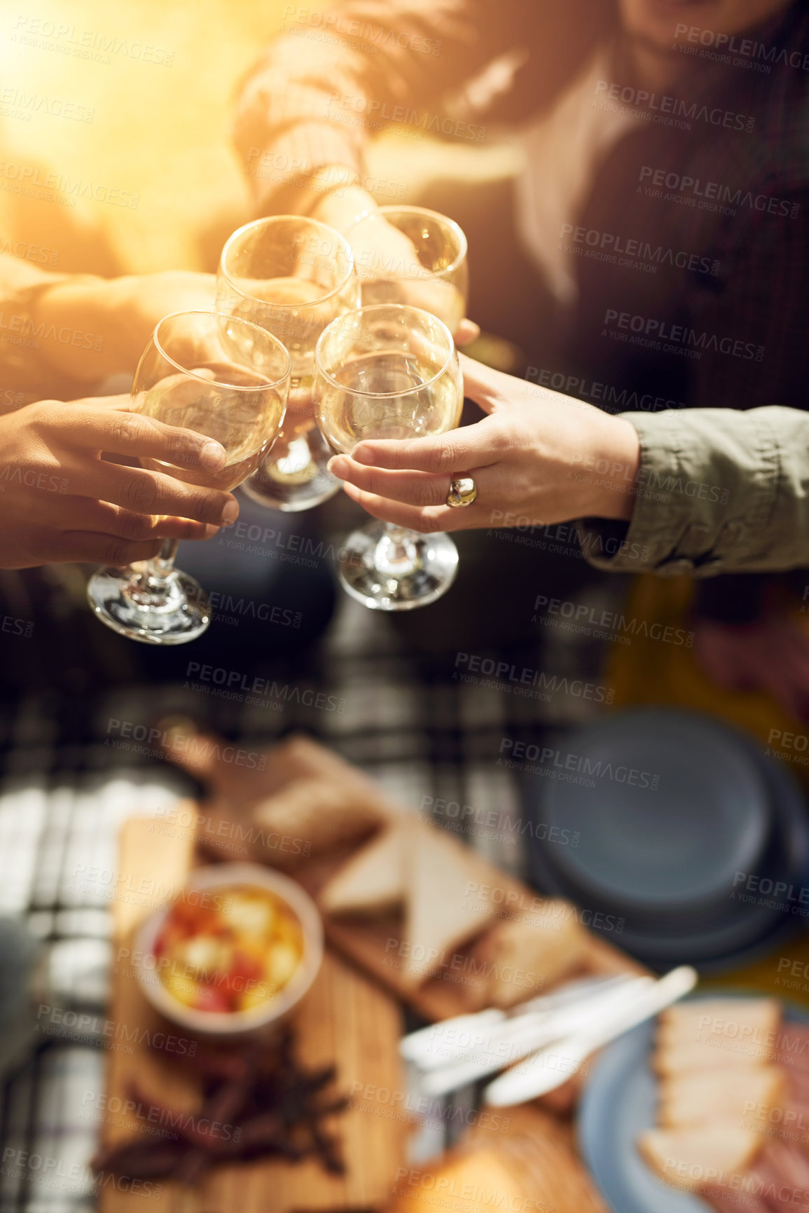 Buy stock photo Friends, picnic and hands cheers with alcohol on holiday, vacation and adventure outdoors. Lens flare, happy and men and women toast with drinks for social gathering, celebration and fun on weekend