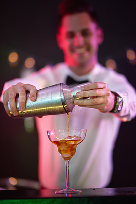Buy stock photo Shot of a bartender pouring a drink into a glass in a nightclub