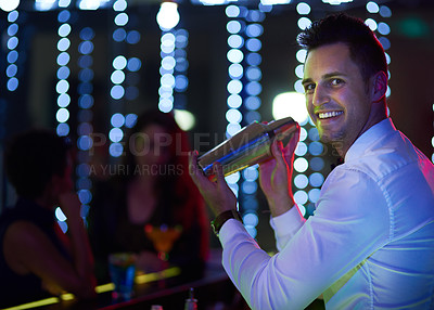 Buy stock photo Portrait of a smiling bartender mixing a drink behind the bar of a nightclub