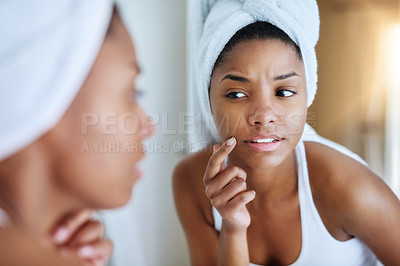 Buy stock photo Shot of a young woman inspecting her skin in front of the bathroom mirror and looking upset