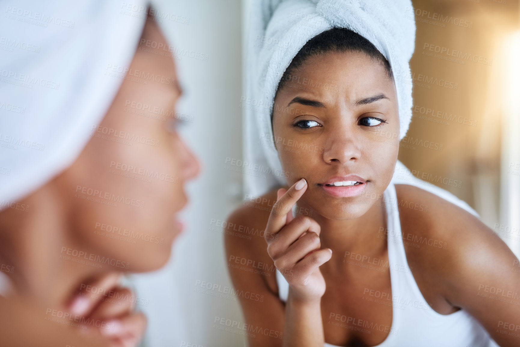 Buy stock photo Shot of a young woman inspecting her skin in front of the bathroom mirror and looking upset