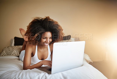 Buy stock photo Shot of a relaxed young woman using a laptop on her bed in the morning