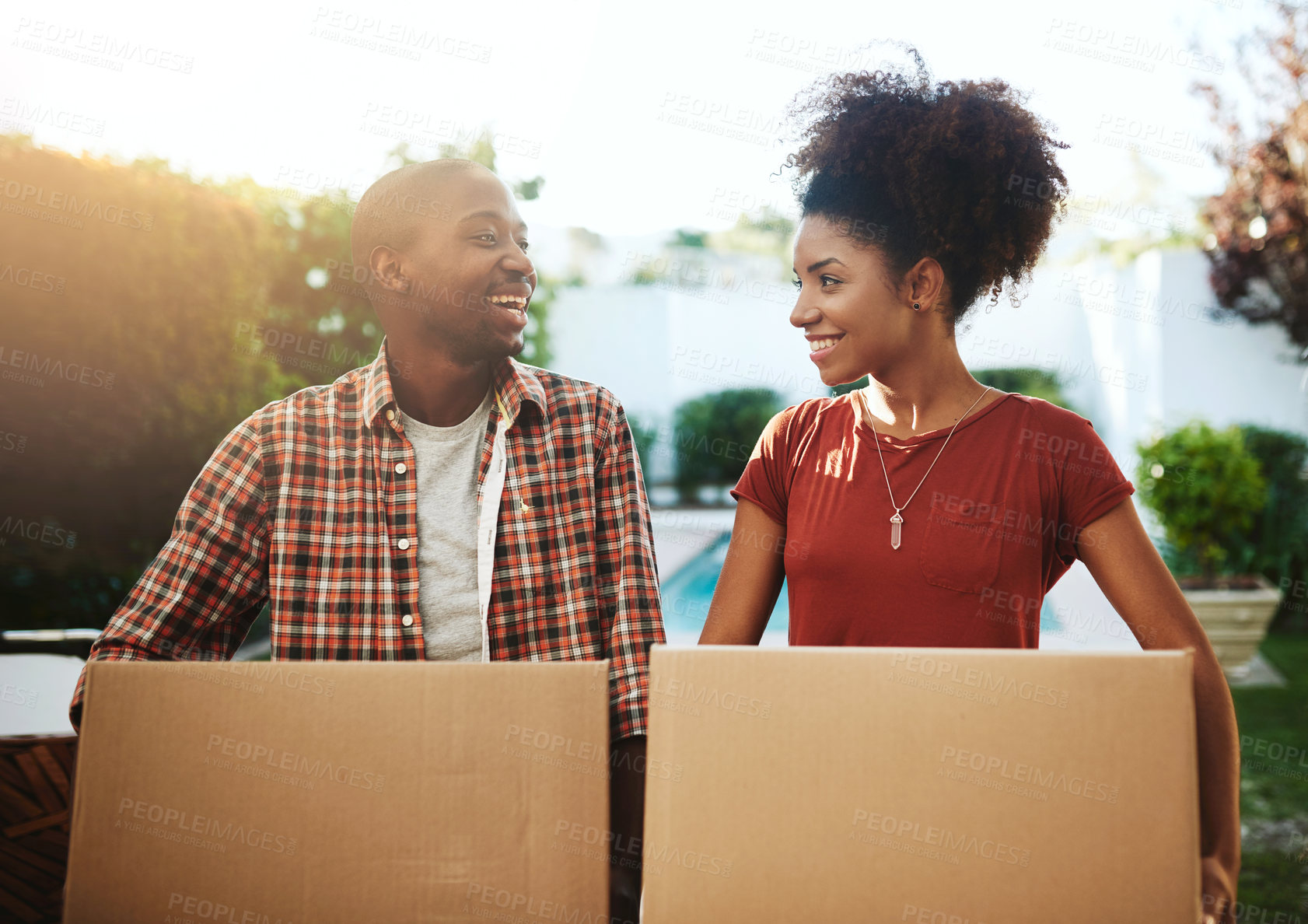 Buy stock photo Cropped shot of a young couple carrying boxes while moving into their new home