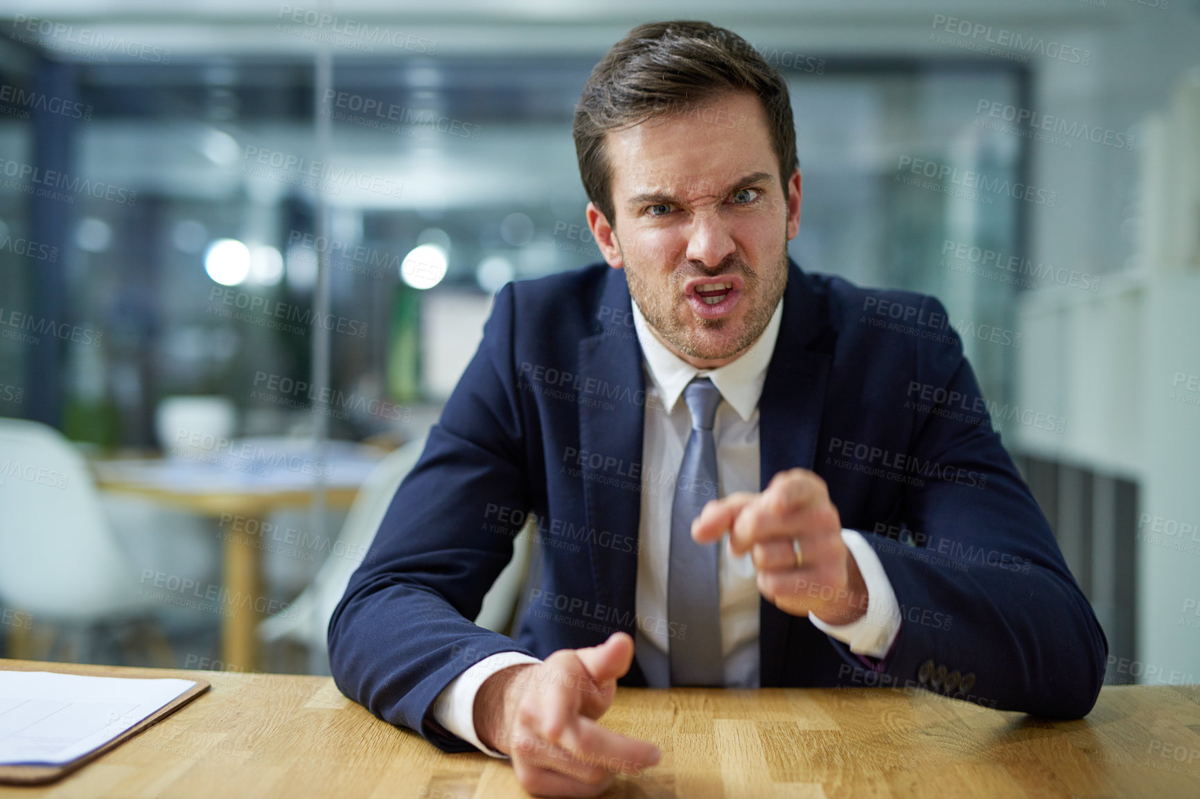 Buy stock photo Portrait of an angry businessman shouting and pointing his finger while sitting at a desk