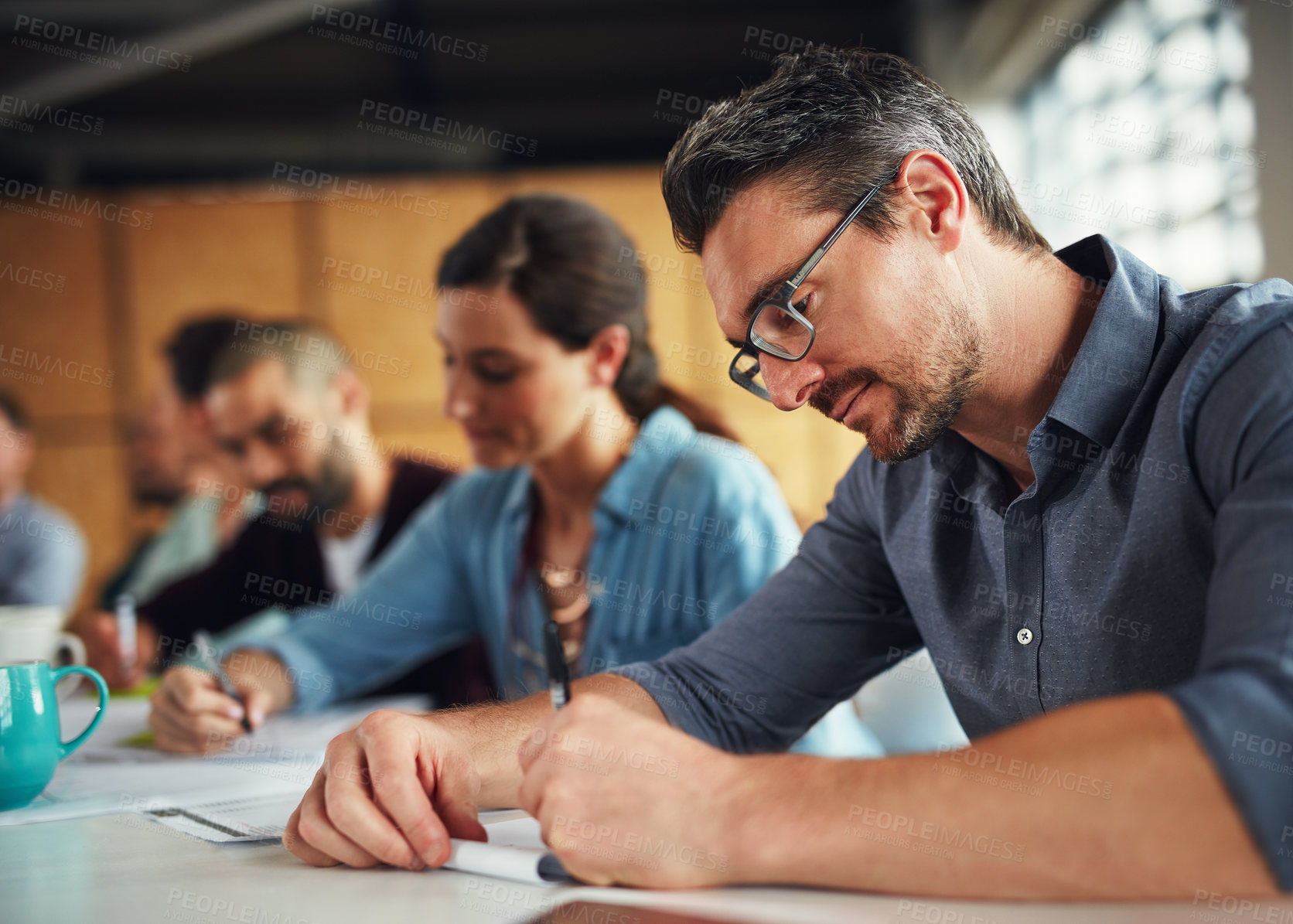 Buy stock photo Shot of a group of colleagues working together at a table in an office