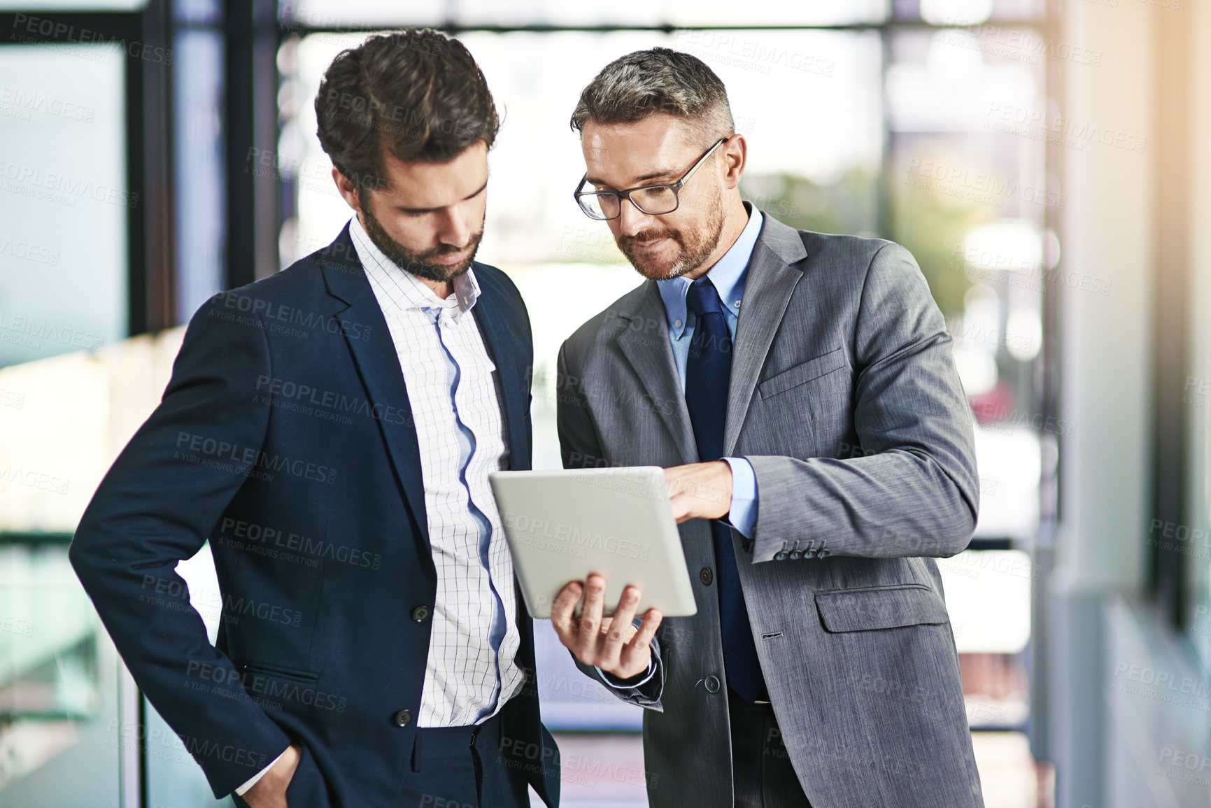 Buy stock photo Cropped shot of two businessmen working together on a digital tablet in an office