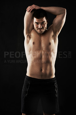 Buy stock photo Studio portrait of a sporty young man stretching his arms isolated on black