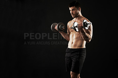 Buy stock photo Studio shot of a sporty young man working out with dumbbells isolated on black