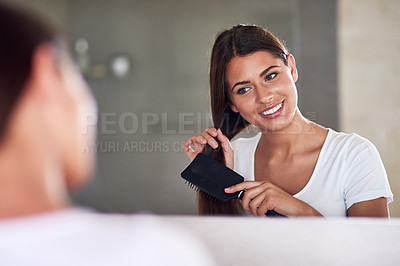 Buy stock photo Shot of a beautiful young woman brushing her hair in front of the mirror at home