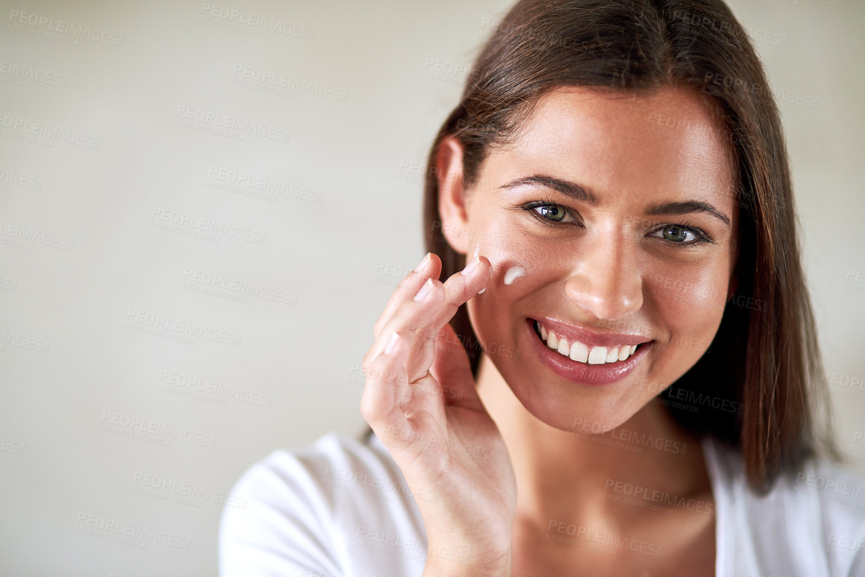 Buy stock photo Portrait of a beautiful woman applying moisturizer to her perfect skin