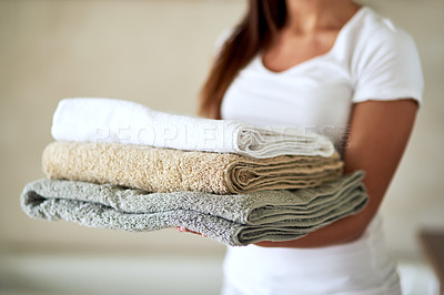 Buy stock photo Shot of an unidentifiable woman holding a pile of clean towels