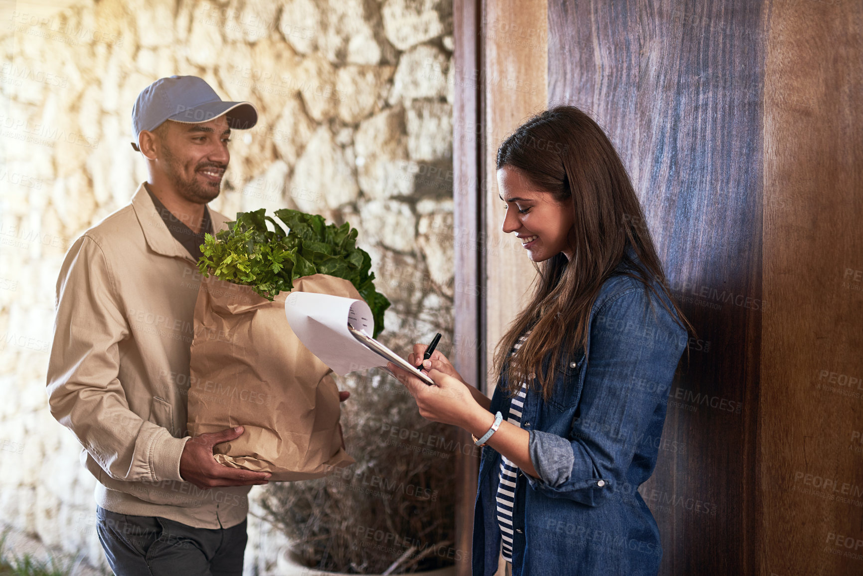 Buy stock photo Cropped shot of a courier making a delivery to a customer at her home