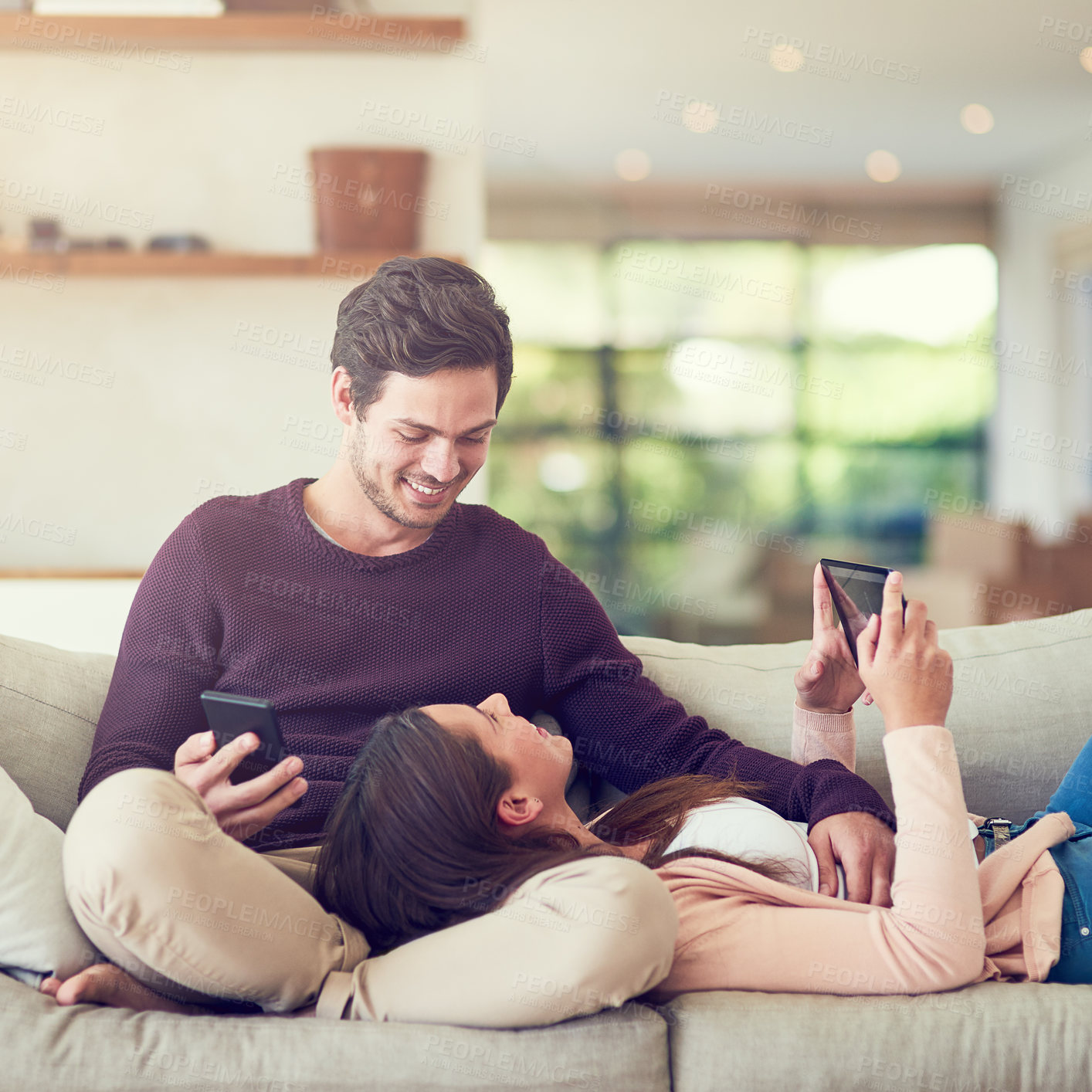 Buy stock photo Tablet, cellphone and couple relaxing in living room for entertainment together on sofa at home. Happy, love and people online networking on a phone and digital technology in lounge at apartment.