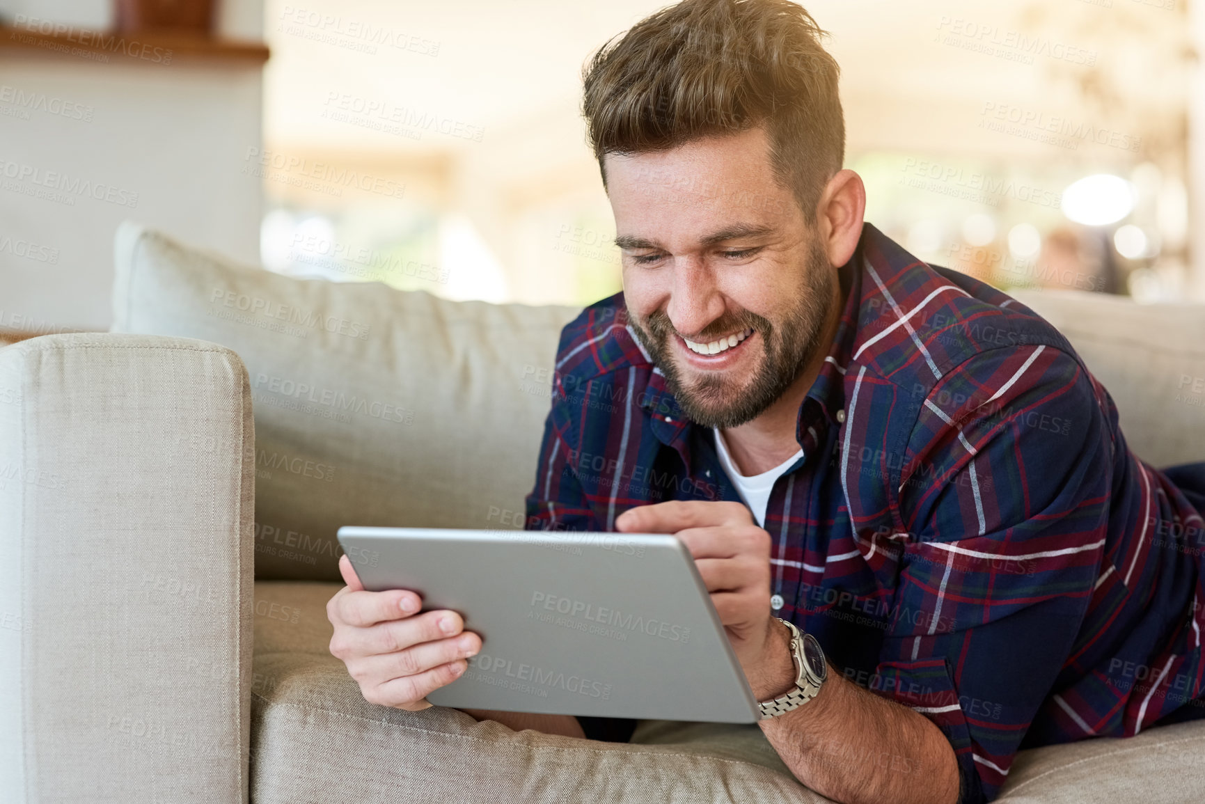 Buy stock photo Shot of a relaxed young man using a digital tablet on the sofa at home