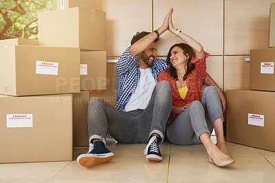 Buy stock photo Shot of a young couple high fiving while moving into their new home