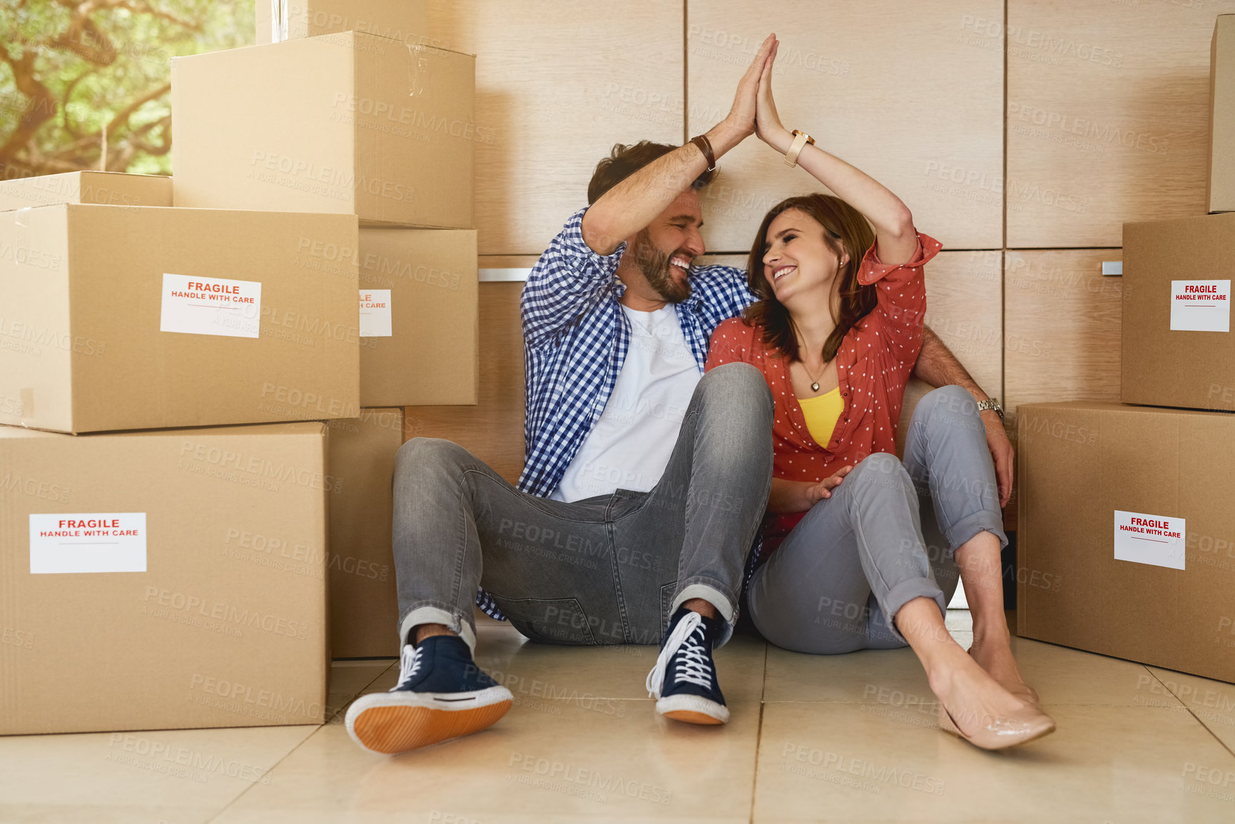 Buy stock photo Shot of a young couple high fiving while moving into their new home