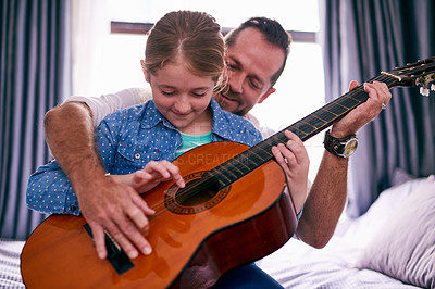 Buy stock photo Cropped shot of a father and daughter playing the guitar together at home