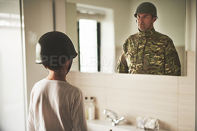 Buy stock photo Rearview shot of a young boy wearing an army helmet seeing his father's reflection in the mirror