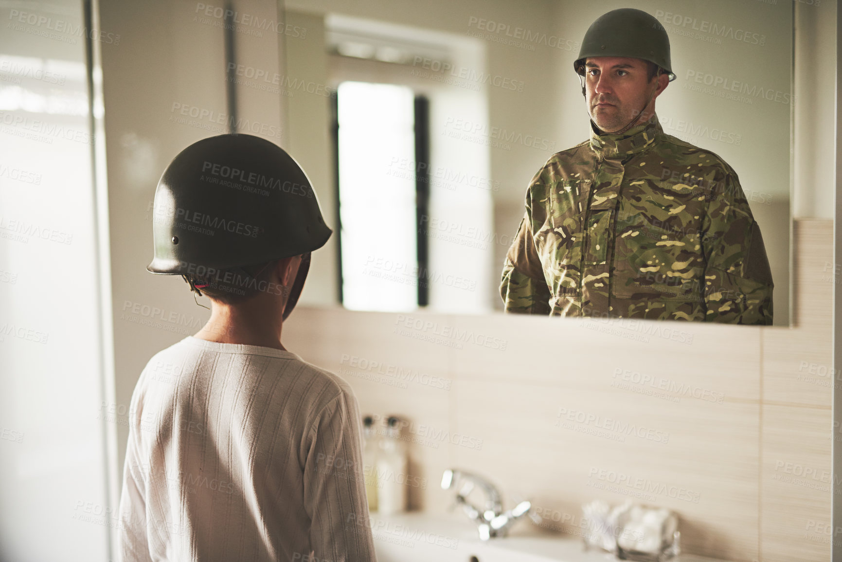 Buy stock photo Rearview shot of a young boy wearing an army helmet seeing his father's reflection in the mirror