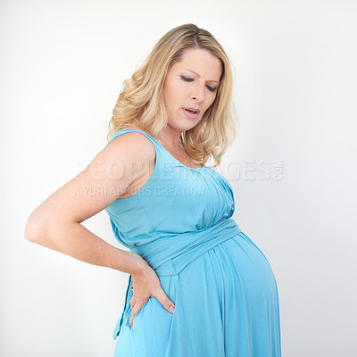 Buy stock photo Shot of a pregnant woman experiencing back pain against a white background