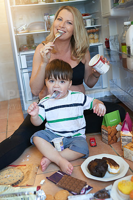 Buy stock photo Portrait of a pregnant woman and her baby eating treats while sitting on the kitchen floor