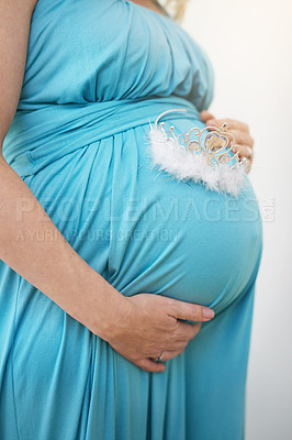 Buy stock photo Shot of an unidentifiable pregnant woman holding a tiara against her belly